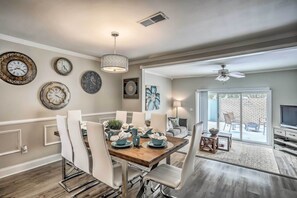 A dining area with a wooden table, white chairs, and a chandelier. - Walk to Ocean & Family Fun: Myrtle Beach Townhome! (Myrtle Beach)