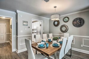 A dining area with a wooden table, white chairs, and a chandelier.