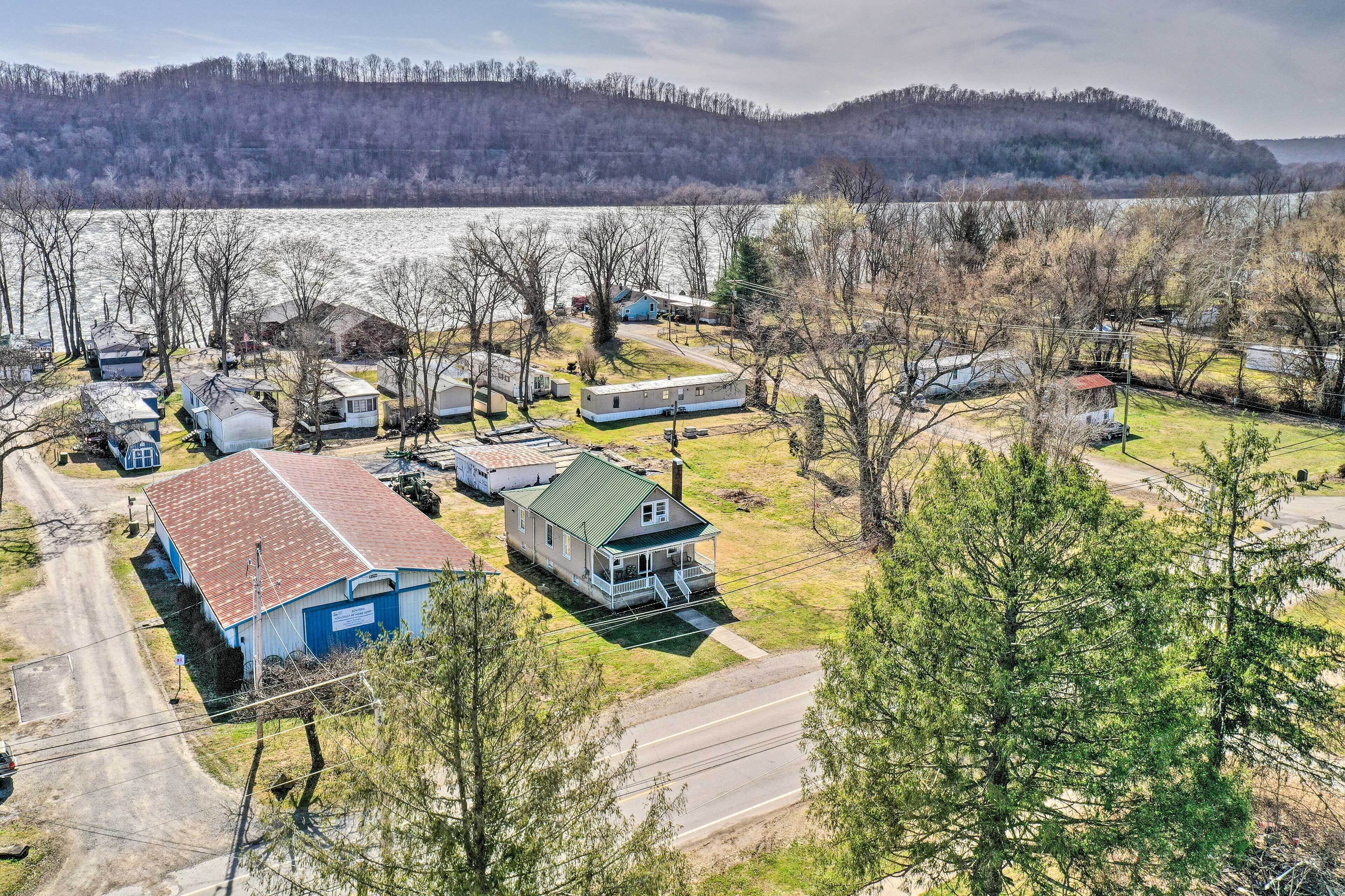 A residential area with multiple houses and trailers, a road, and a body of water in the background.