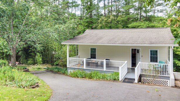 A small, single-story house with a porch, surrounded by lush greenery. - 4 Mi to Main Street: Petite Weaverville Escape! (Weaverville)