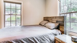 A bedroom with a bed, a wooden headboard, a nightstand, and a window with a view of greenery. - 4 Mi to Main Street: Petite Weaverville Escape! (Weaverville)