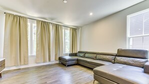A modern living room with a sectional sofa, a small ottoman, and a wooden floor. - Updated Charlotte Vacation Rental 4 Mi to Downtown (Charlotte)