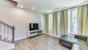 A modern living room with a flat-screen TV, a leather sofa, and a wooden floor. - Updated Charlotte Vacation Rental 4 Mi to Downtown (Charlotte)