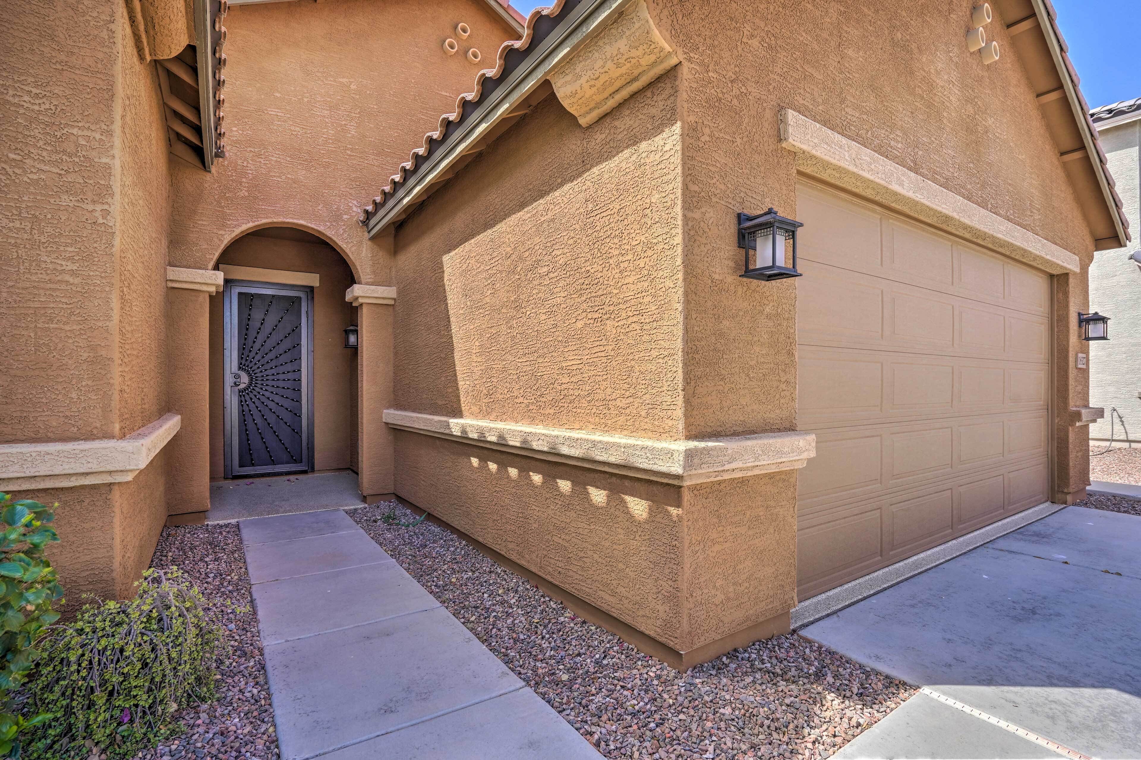 A house with a stucco exterior, a garage door, and a decorative door with a fan-like pattern.