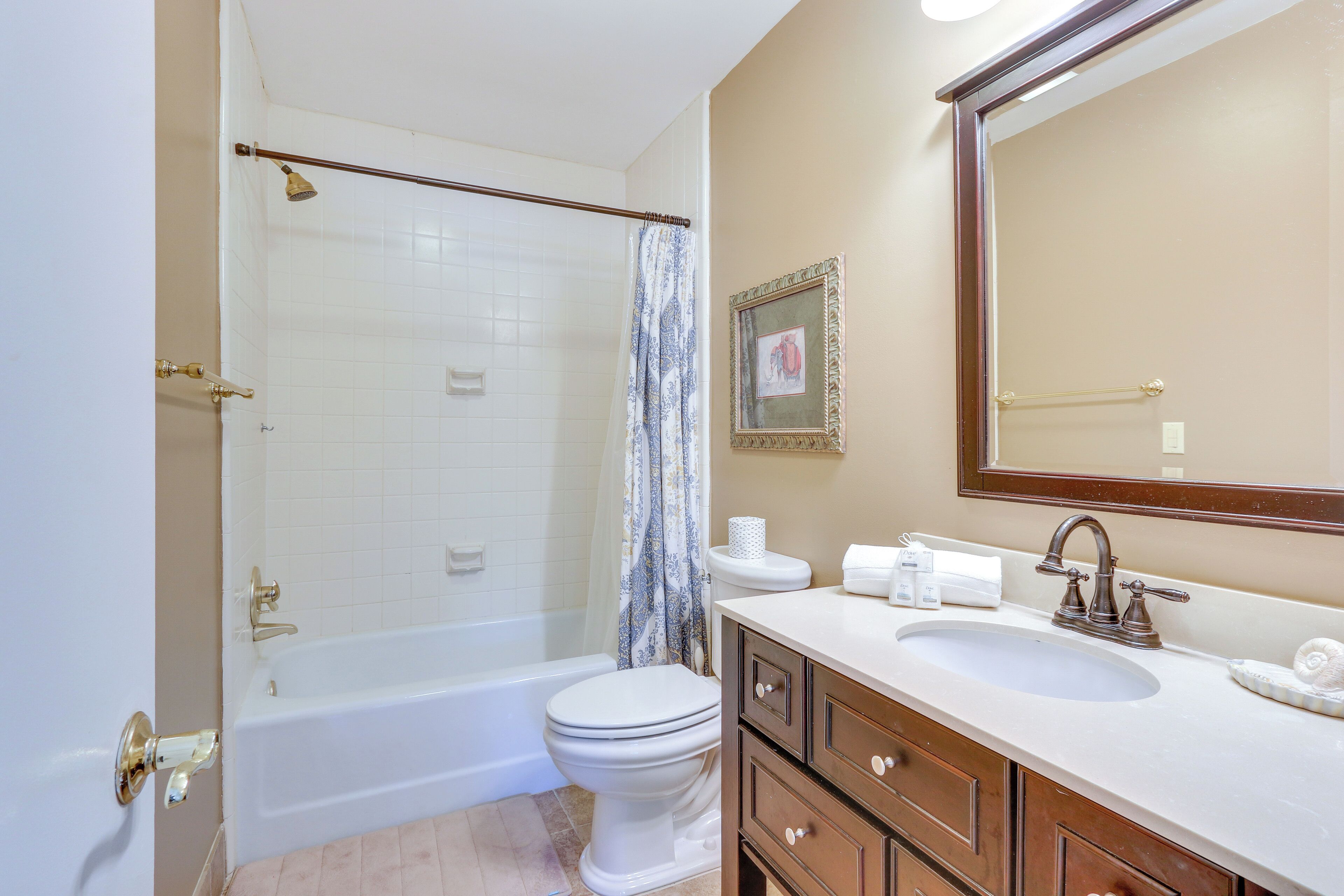A bathroom with a bathtub, toilet, sink, and a large mirror.