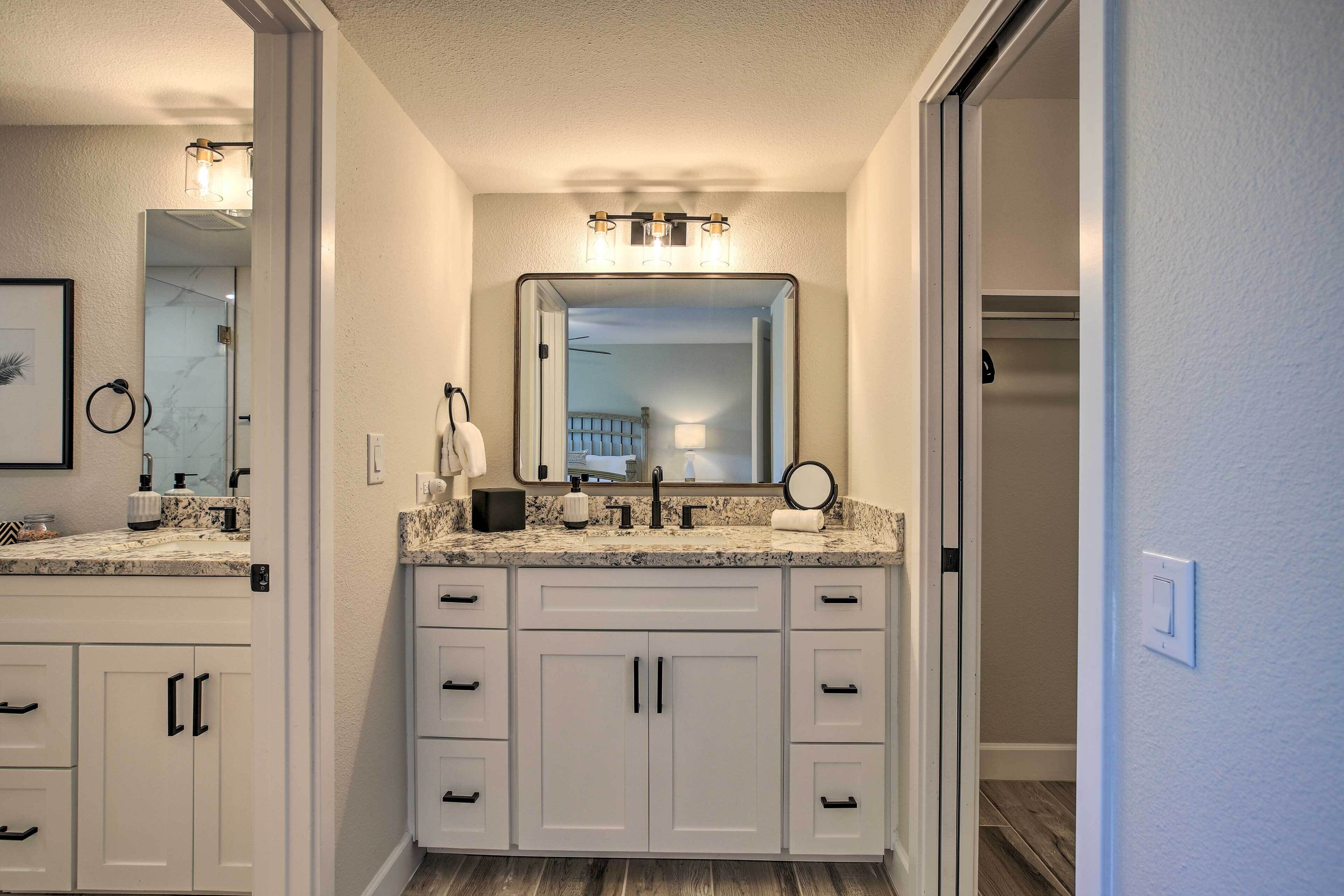 A bathroom with a double vanity, a large mirror, and a light fixture above the mirror.