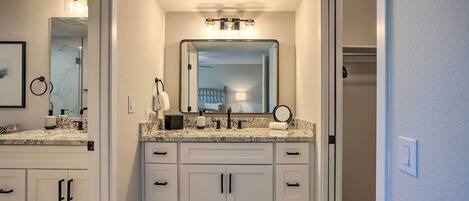 A bathroom with a double vanity, a large mirror, and a light fixture above the mirror.