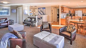 A spacious living area with leather sofas, a grey ottoman, and a dining area with wooden chairs and a table. - Stunning Kent Lake House w/ Private Dock! (Covington)