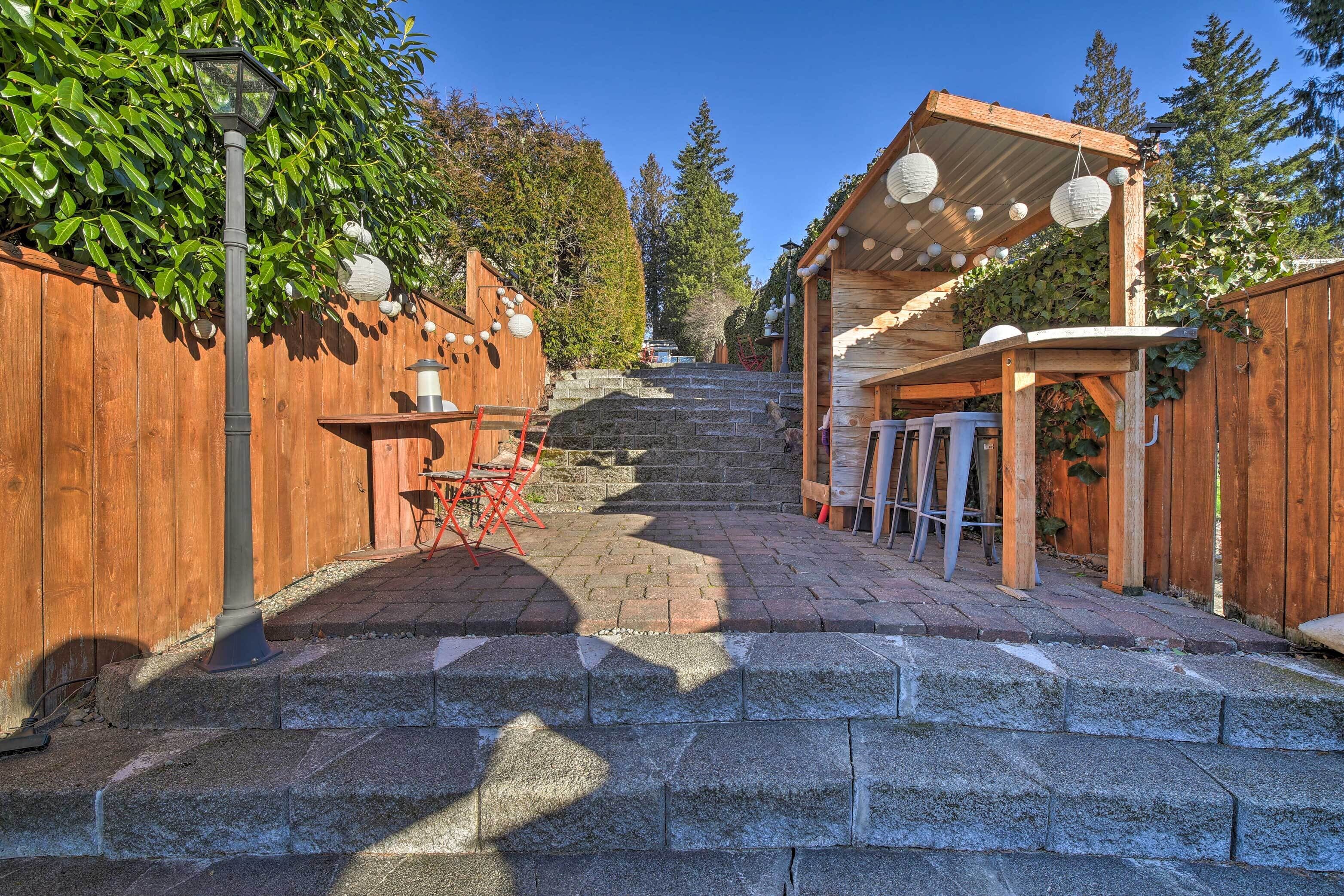 A wooden deck with a pergola, stone steps, and a lantern post.