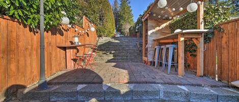 A wooden deck with a pergola, stone steps, and a lantern post.