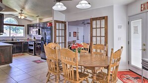 A spacious kitchen with dark cabinets, a central island, and a dining area with wooden chairs and a round table. - Home w/ Game Room & Fire Pit: 30 Min to Zion! (La Verkin)