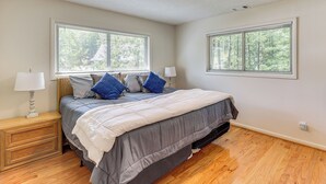 A bedroom with a bed, two bedside lamps, a nightstand, and two windows with blinds. - Beautiful Lakefront Home With Plenty of Space! (Jacksons' Gap)