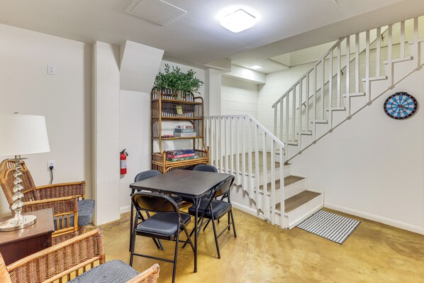 A dining area with a table and chairs, a bookshelf, and a staircase.