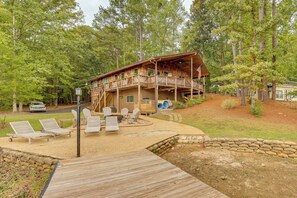 A cabin with a deck, outdoor seating, and a stone wall.