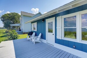 A blue house with a porch, white shutters, and a small deck with two Adirondack chairs. - Waterfront Vacation Rental Home on Newport River! (Beaufort)