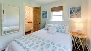 Un dormitorio con una cama grande, una puerta de madera, un baño y una lámpara fijada a la pared.