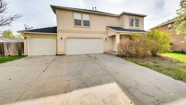 A two-story house with a garage and a driveway. - Ideally Located Nampa Home w/ Office Area & Patio! (Nampa)