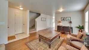 A spacious living room with hardwood floors, a wooden coffee table, patterned sofas, and a staircase leading to another level. - Ideally Located Nampa Home w/ Office Area & Patio! (Nampa)