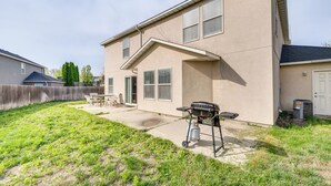 A residential house with a backyard, a barbecue grill, and a patio area. - Ideally Located Nampa Home w/ Office Area & Patio! (Nampa)