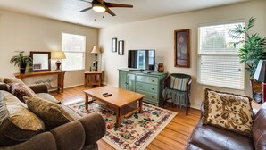 A living room with a ceiling fan, wooden furniture, a television, and a green cabinet. - Ideally Located Nampa Home w/ Office Area & Patio! (Nampa)