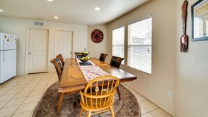 A dining room with a wooden table, chairs, a fruit bowl, and a clock on the wall. - Ideally Located Nampa Home w/ Office Area & Patio! (Nampa)