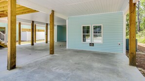 Ein überdachter Außenbereich mit einem hellblauen Gebäude, Holzbalken und einem Betonboden.