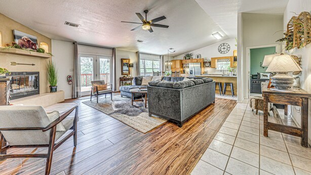 A spacious living room with a gray sofa, wooden flooring, and a ceiling fan. - Charming Ruidoso House w/ Deck & Mountain Views! (Ruidoso)