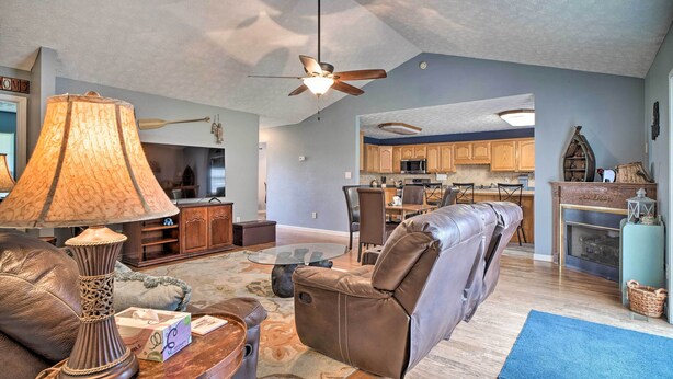 A living room with a leather sofa, a glass coffee table, and a floor lamp. There is a ceiling fan and a fireplace. - Charming 'hideaway Haven' Near Pigeon Forge! (Dandridge)