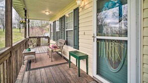A covered porch with a wooden deck, wicker furniture, and a green table. - Charming 'hideaway Haven' Near Pigeon Forge! (Dandridge)