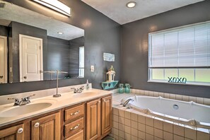 A bathroom with two sinks, a bathtub, wooden cabinets, a mirror, and a window with blinds. - Charming 'hideaway Haven' Near Pigeon Forge! (Dandridge)