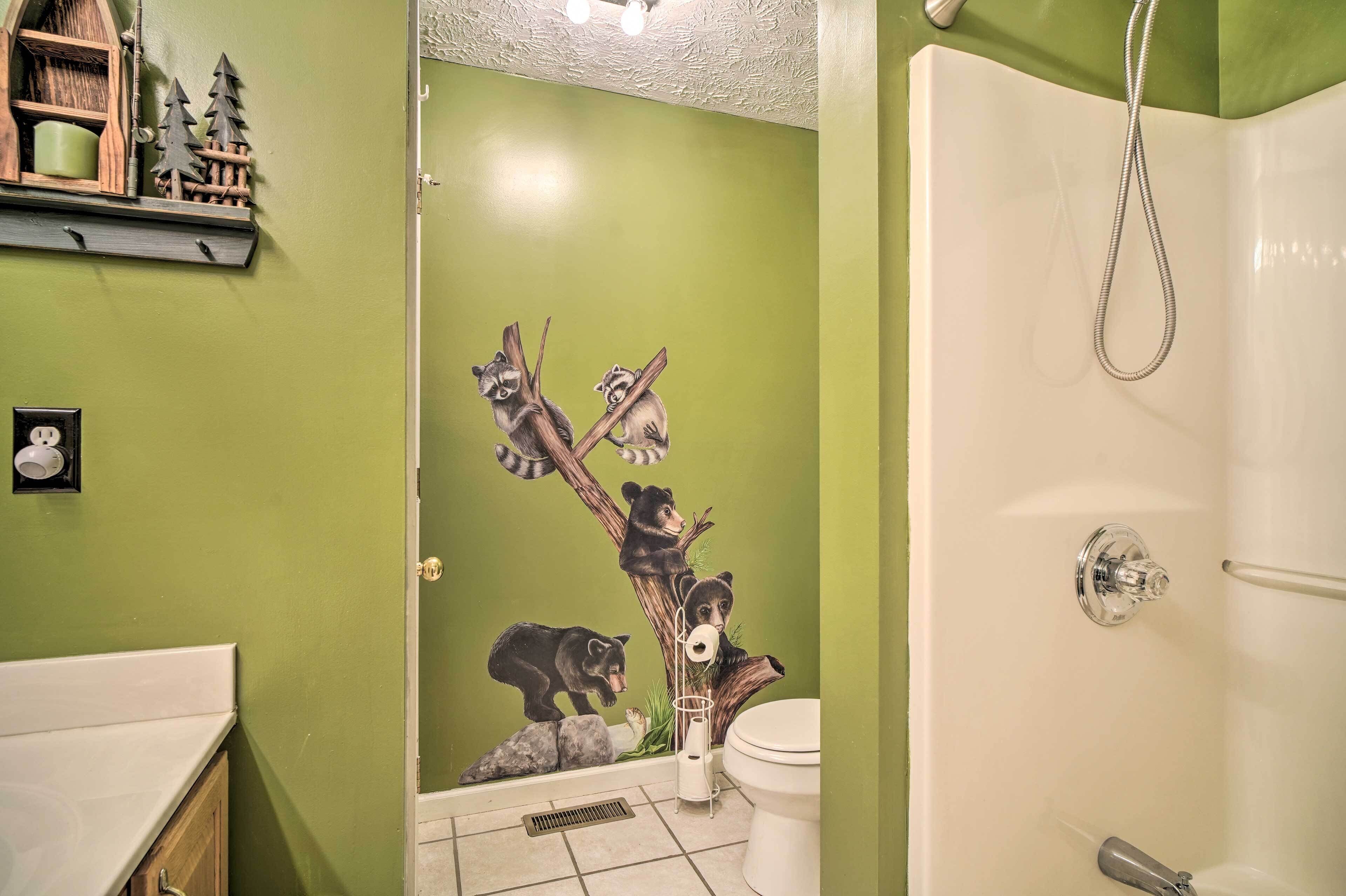 A bathroom with a green wall, a white bathtub, and a shower with a handheld showerhead.