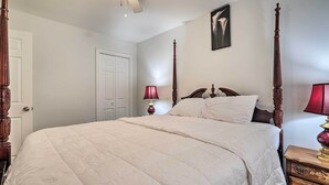 A neatly made bed with a white quilt, a wooden headboard, and two bedside lamps. - Maryland Vacation Home Near US Capital! (Riverdale)