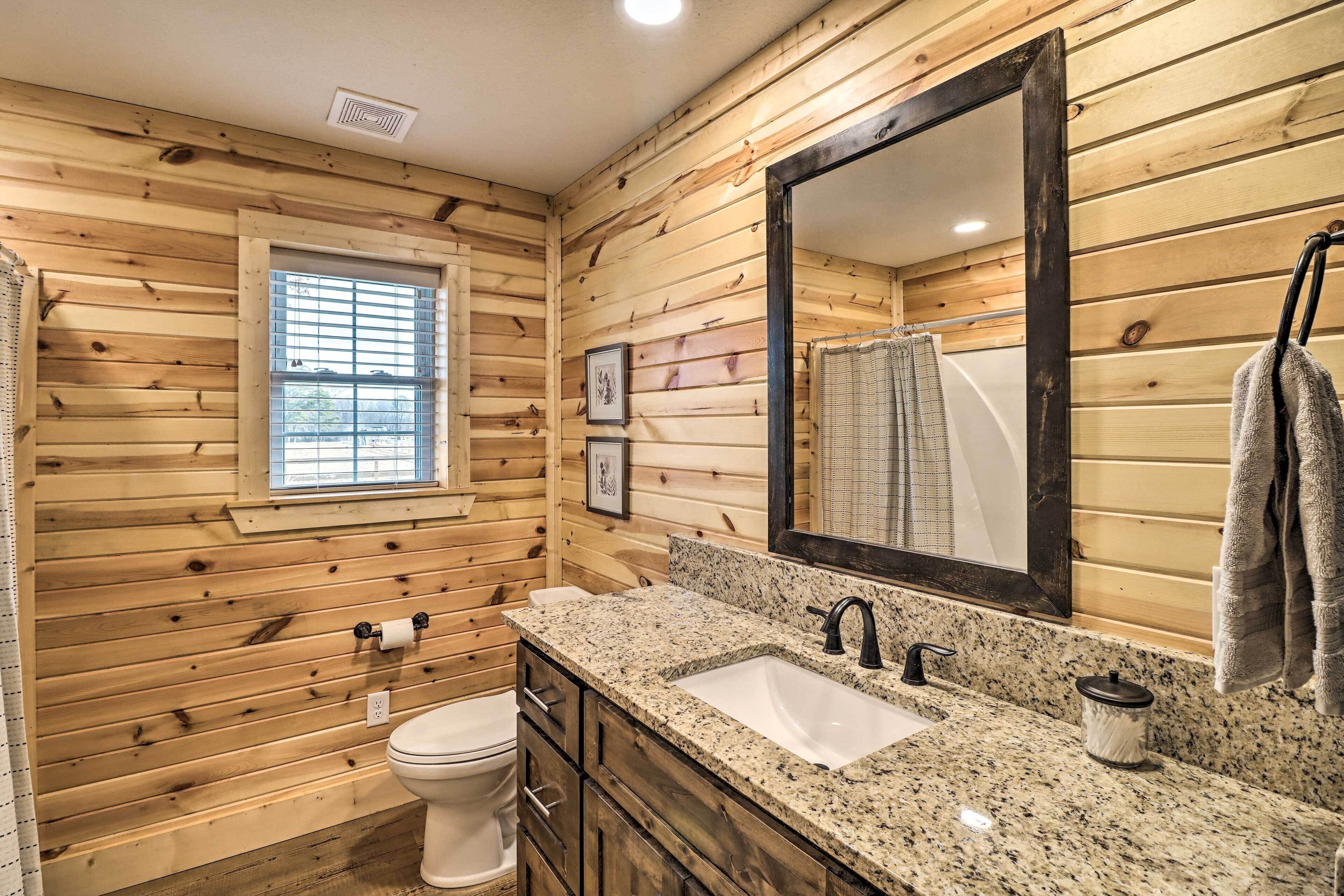 Un baño con paredes de madera, un ventanal, un lavamanos y un espejo.