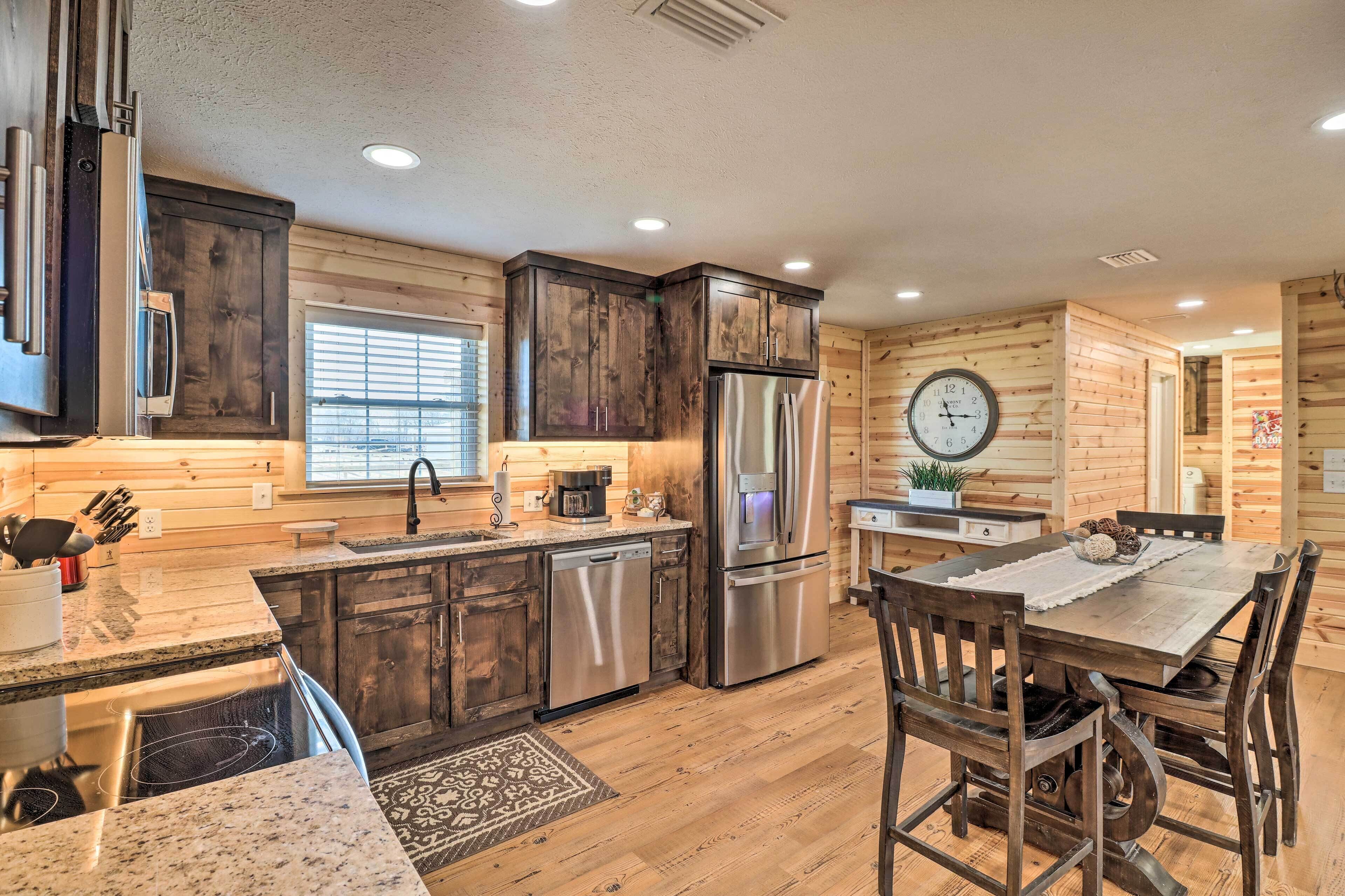 A kitchen with wooden cabinets, stainless steel appliances, a clock, and a dining area with a table and chairs.