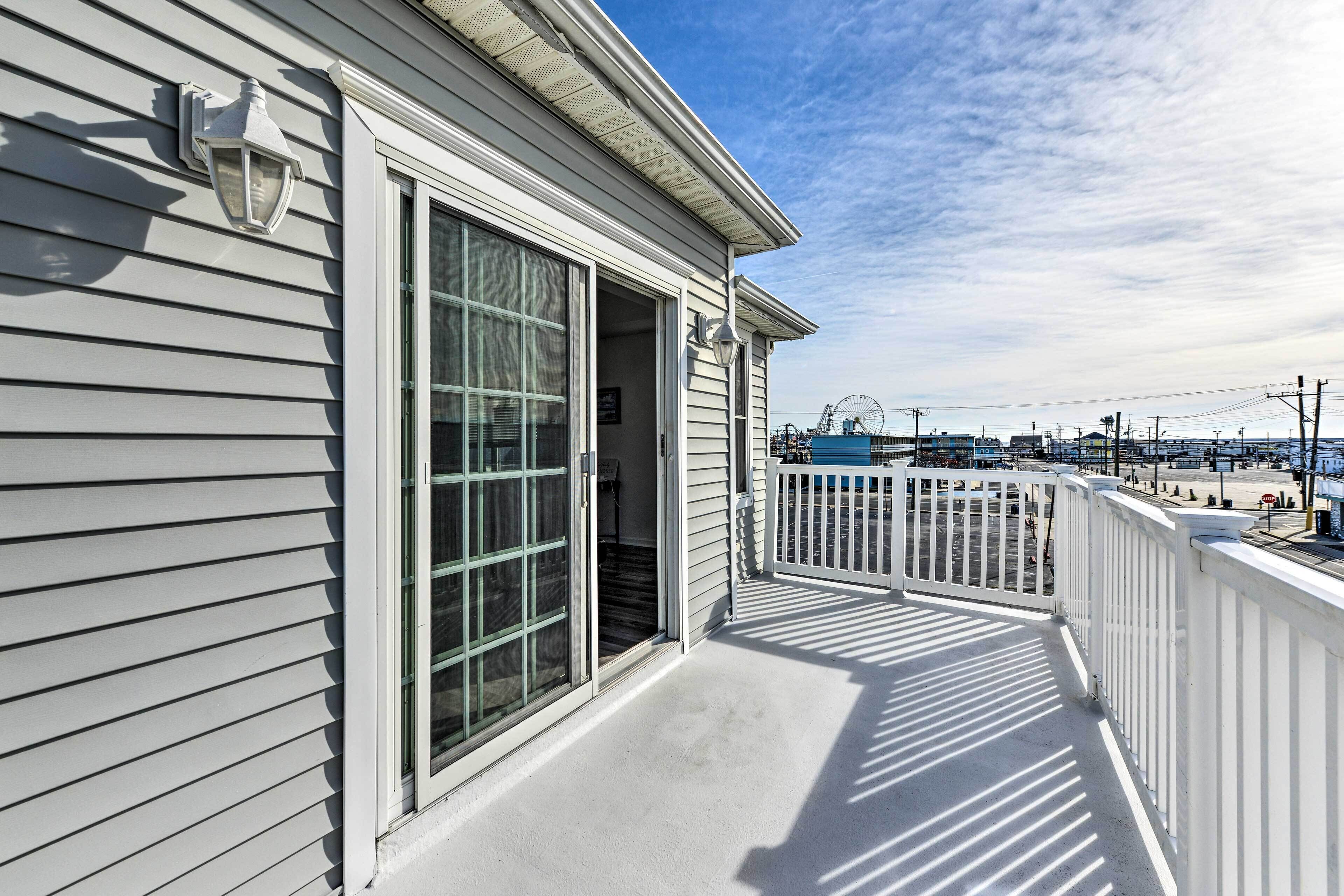 A balcony with a white railing, a large sliding glass door, and a view of a pier with boats.