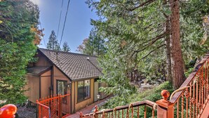 A wooden cabin with a red staircase and a view of surrounding trees.