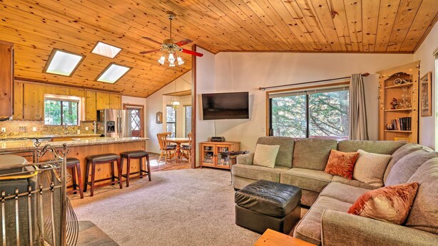 A spacious living area with a wooden ceiling, a large window, a television, and a cozy seating arrangement.