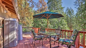 A deck with a grill, a table, chairs, and an umbrella.