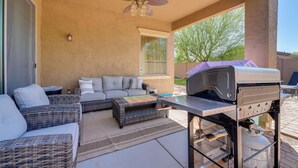 Een overdekt terras met buitenmeubilair, een plafondventilator en een barbecue.