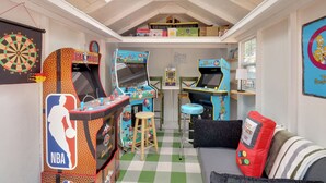 Una habitación con juegos de arcade, un sofá y un dardo.