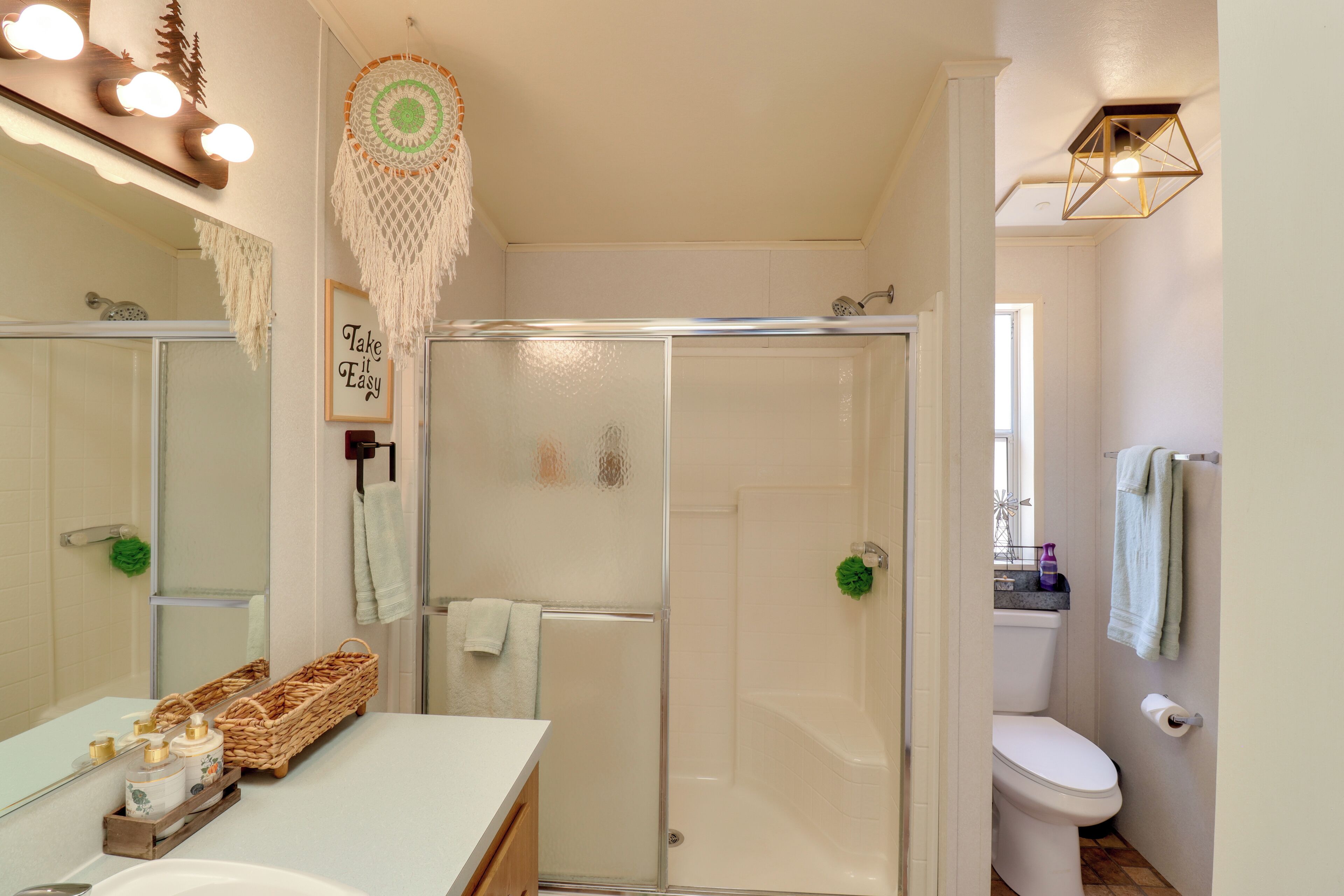 A bathroom with a glass-enclosed shower, a white sink, and a mirror.