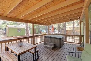 Una terrazza coperta con tavolo e panche in legno, una vasca idromassaggio e una casetta per bambini sullo sfondo.