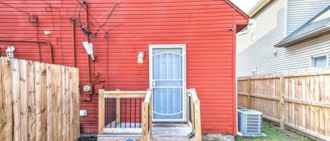 Un bâtiment rouge avec une porte bleue, une clôture en bois et un panneau d’avertissement de sécurité.