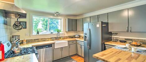 A modern kitchen with stainless steel appliances, a wooden island, and a window providing natural light.