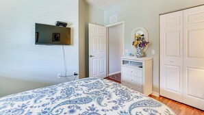 Une chambre à coucher avec un lit, une commode, un miroir et une porte.