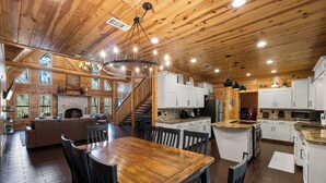 A spacious kitchen with wooden cabinets, a large island, and a dining area with a wooden table and chairs. - Broken Bow Family Cabin w/ Private Hot Tub! (Broken Bow)