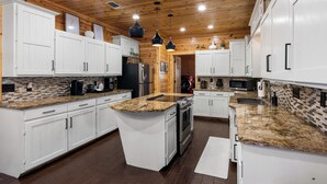 A modern kitchen with white cabinets, granite countertops, stainless steel appliances, and wooden ceiling. - Broken Bow Family Cabin w/ Private Hot Tub! (Broken Bow)