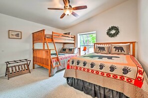 A bedroom with bunk beds, a ceiling fan, a window with a view, and a wall decoration.