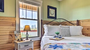 A bedroom with a wooden headboard, a quilted bedspread, a bedside table with a lamp, and a window with blinds. - Near Wineries & Hiking: Lawndale Home w/ Fire Pit! (Lawndale)