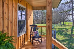 A wooden porch with a rocking chair and a view of a green field and trees. - Near Wineries & Hiking: Lawndale Home w/ Fire Pit! (Lawndale)